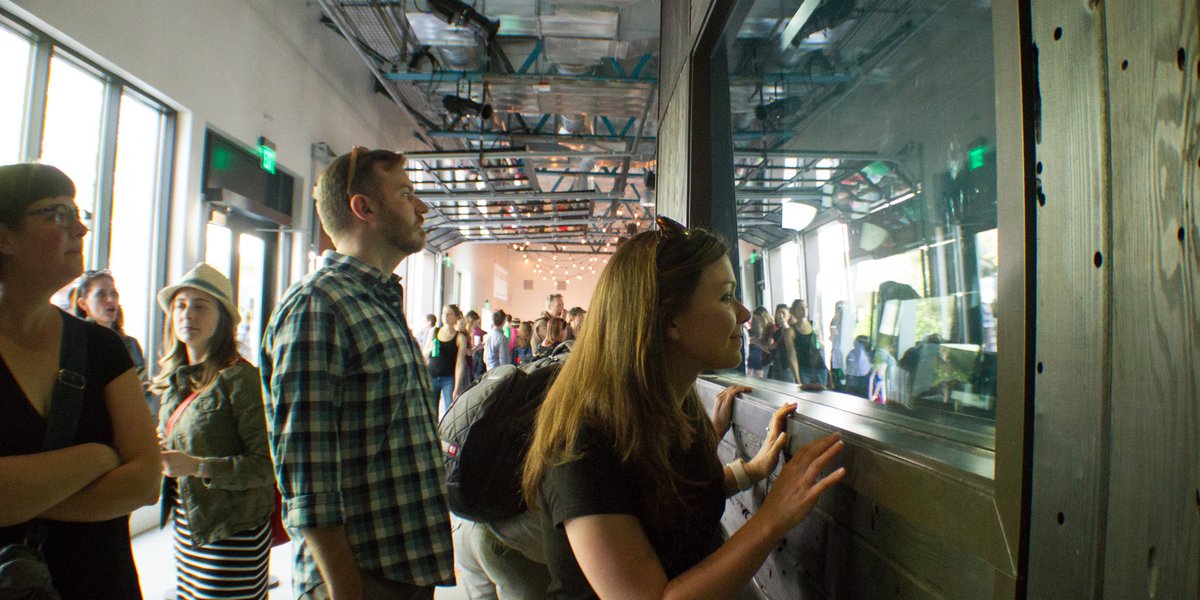 Tour guests looking through a window into a DJ booth
